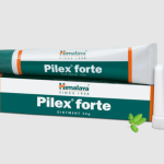 A tube of Himalaya Pilex Forte Ointment is displayed on its box, which is designed in green, white, and orange colors. The packaging features the brand name "Himalaya" and the text "Ointment 30g." A cap and a small green leaf graphic are also visible.